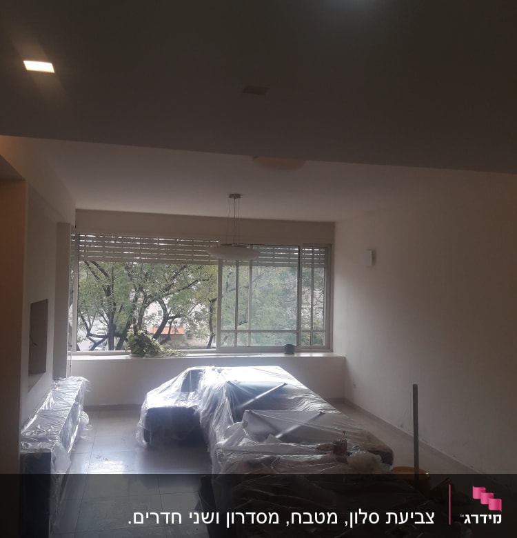חדר עם רהיטים מכוסים בניילון לקראת צביעה